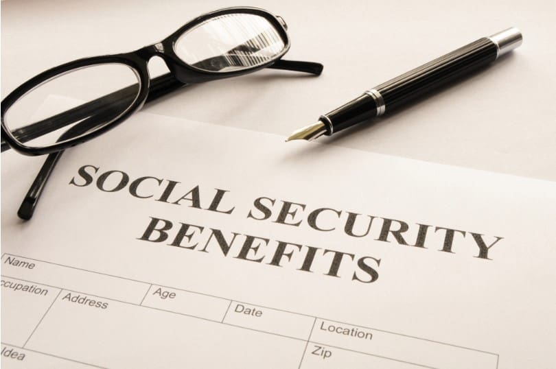 A pen and glasses sitting on top of a social security benefits form.