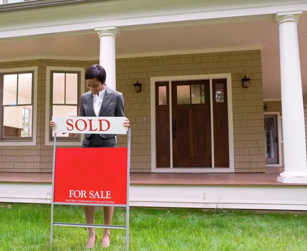 Woman holding a sold real estate sign.