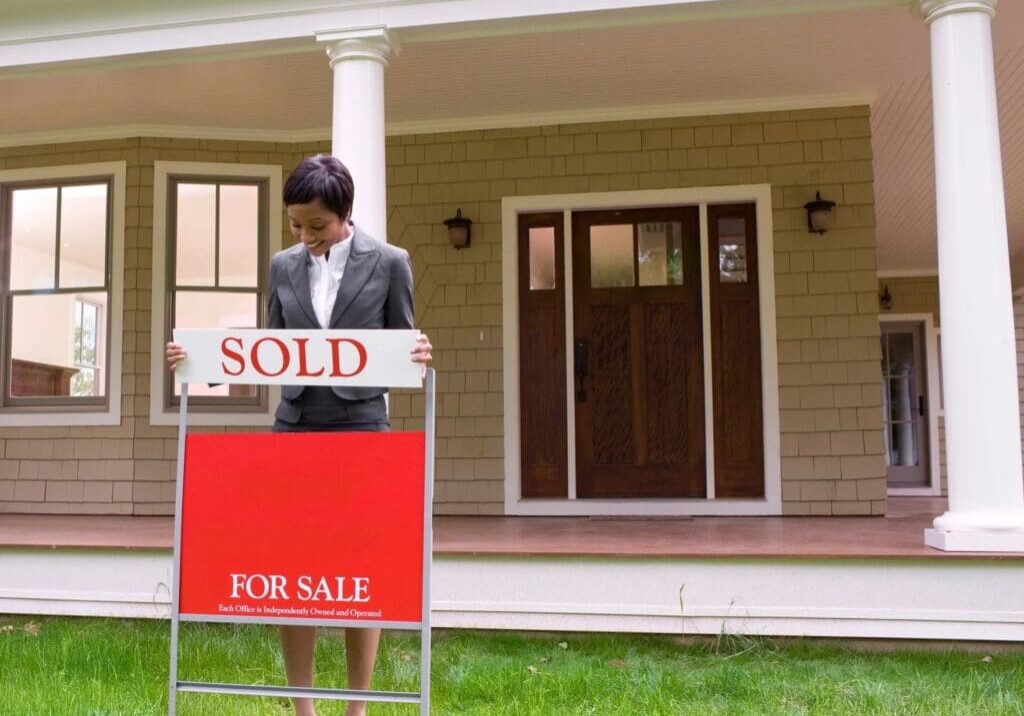 Woman holding a sold real estate sign.