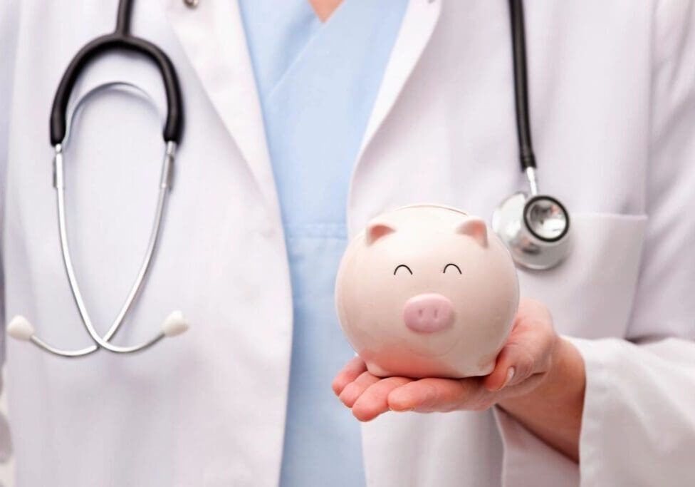 A doctor holding a piggy bank in front of him.