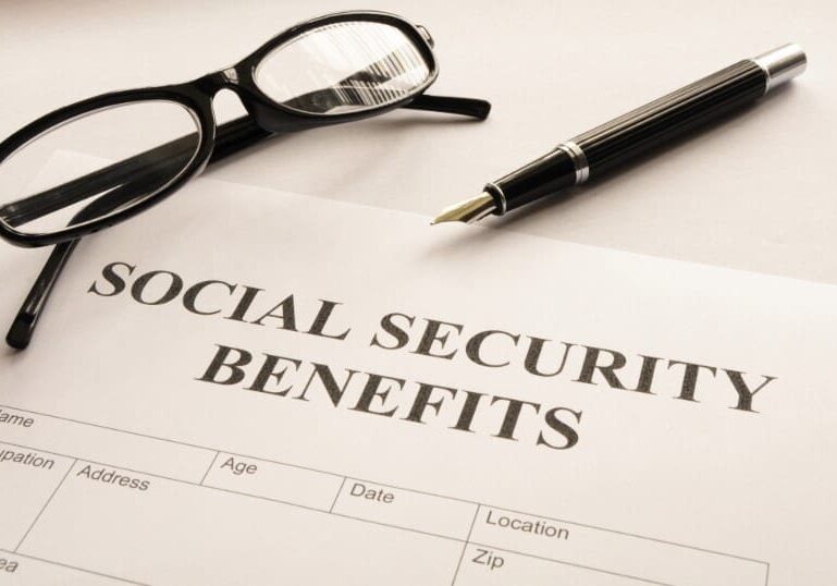 A pen and glasses sitting on top of a social security benefits form.